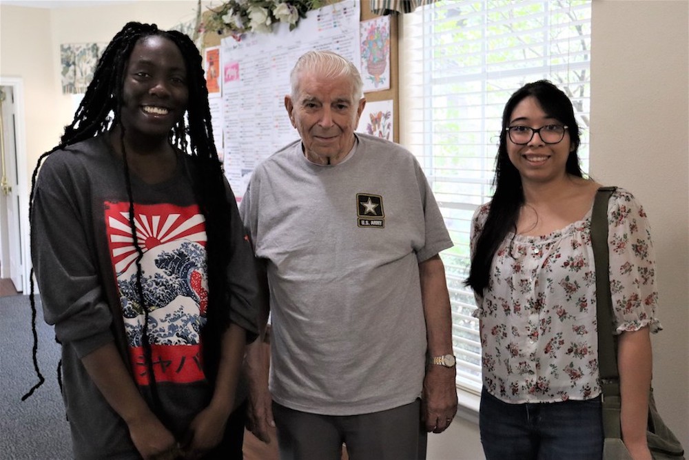 SHSU students, Adetokunbo "Maureen" Ogunleye, and Natalia Ocanas, pose beside Fred Jones. The students created a short video retelling his love story.